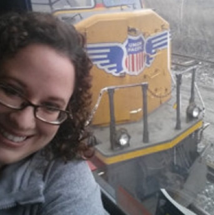 Ashley Robbins smiles in front of a train
