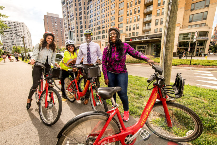 4 people standing with their Capital Bikeshare bikes.