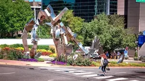 a photo of a large modern art sculpture at an intersection on a busy street