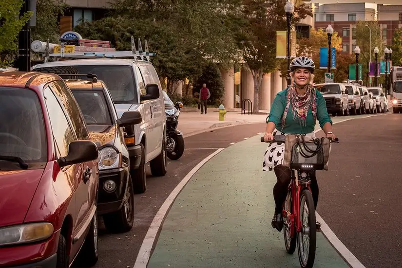 photo of a young lady riding her capital bikeshare bicycle in a green bike lane riding down the street