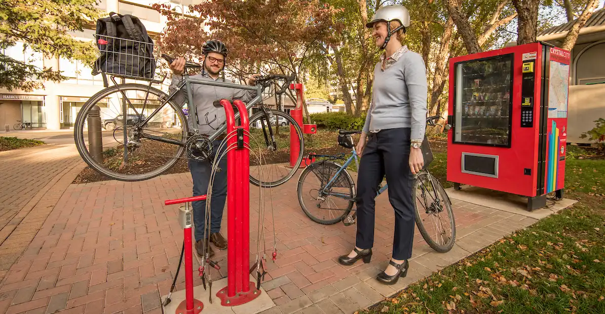 a photo of two bikers doing some mainenance on their bike at a public fix-it station