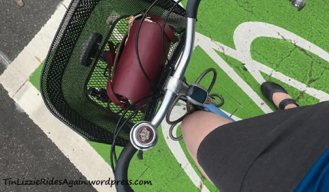 a first person top down photo of a cyclist taking a picture of her bicycle and bicycle basket
